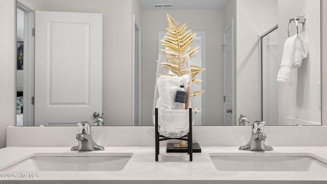 bathroom featuring double vanity, a sink, visible vents, and a shower with door