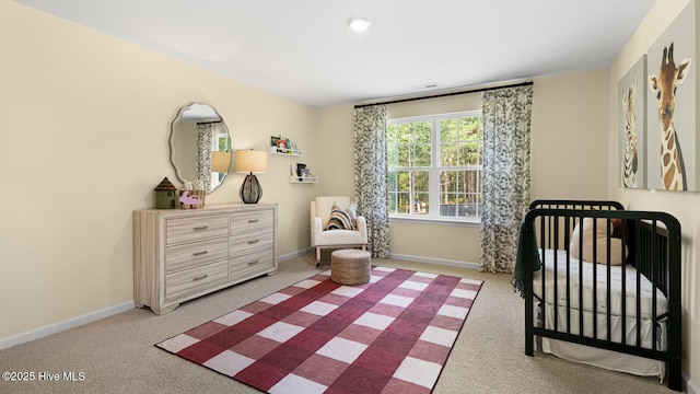 carpeted bedroom featuring a nursery area and baseboards