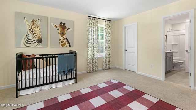 carpeted bedroom featuring ensuite bath and baseboards