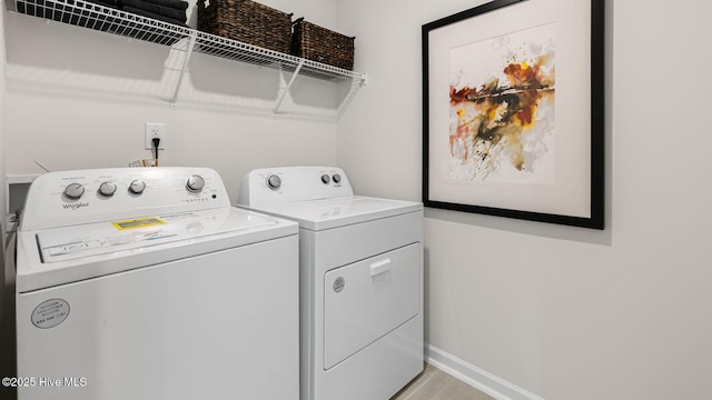 washroom with baseboards, laundry area, and washer and dryer