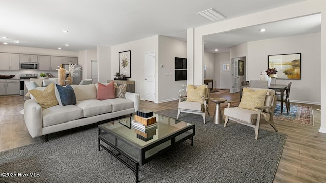 living area featuring light wood-style flooring, baseboards, and recessed lighting