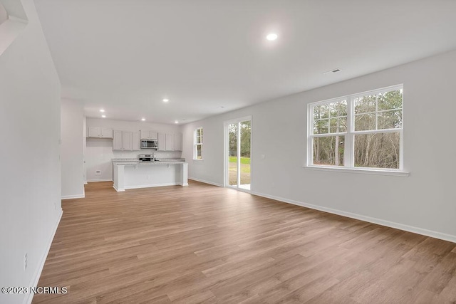 unfurnished living room with visible vents, recessed lighting, baseboards, and light wood-type flooring