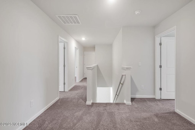 corridor with visible vents, an upstairs landing, baseboards, and carpet flooring