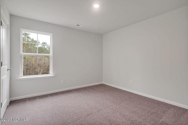 empty room featuring carpet flooring, visible vents, and baseboards