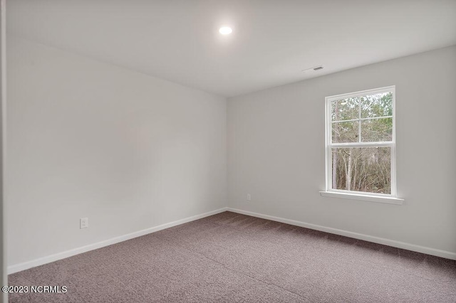 carpeted empty room featuring visible vents and baseboards