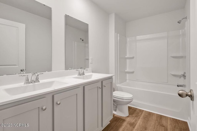 full bathroom with a sink, toilet, wood finished floors, and double vanity