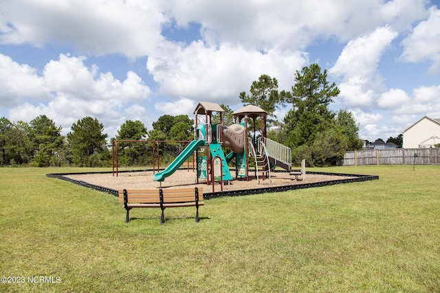 communal playground featuring a lawn and fence