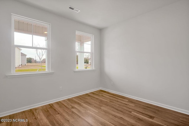 unfurnished room with visible vents, baseboards, and wood finished floors