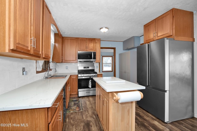 kitchen with brown cabinets, appliances with stainless steel finishes, dark wood finished floors, and a sink