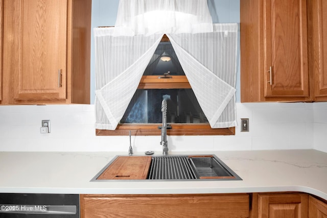 kitchen featuring dishwashing machine, a sink, brown cabinets, light stone countertops, and tasteful backsplash