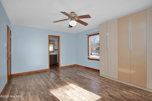 unfurnished bedroom with a ceiling fan, ensuite bath, baseboards, and wood finished floors