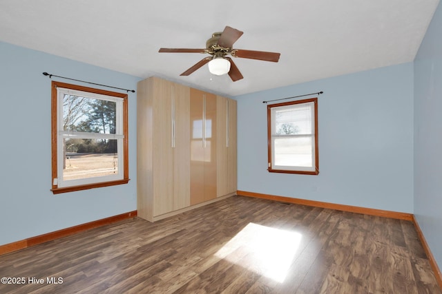 empty room featuring wood finished floors, a wealth of natural light, and baseboards