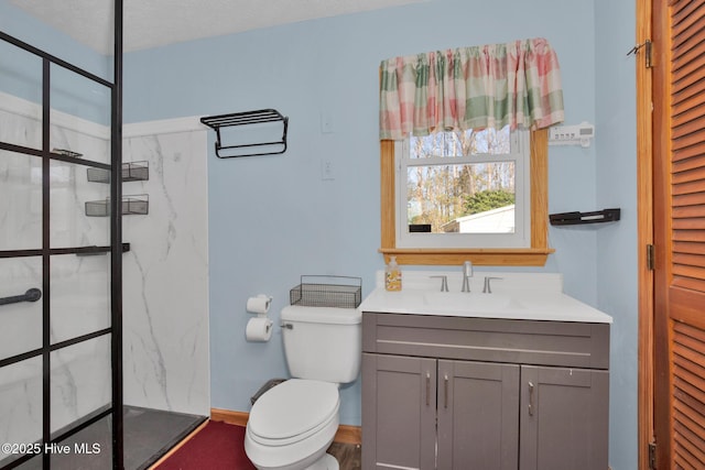 full bath featuring baseboards, toilet, vanity, and a marble finish shower