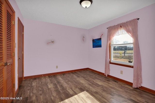 unfurnished bedroom with dark wood-style floors, a closet, and baseboards