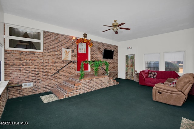 unfurnished living room with brick wall, carpet, and a ceiling fan