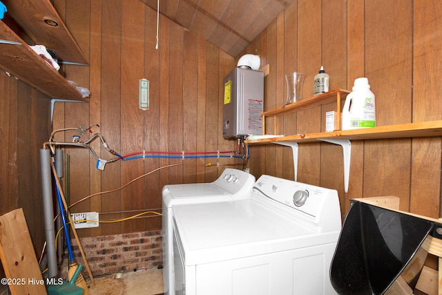 laundry area with tankless water heater, laundry area, independent washer and dryer, and wood walls