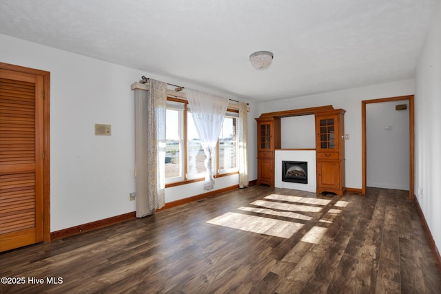 unfurnished living room featuring a fireplace, baseboards, and wood finished floors