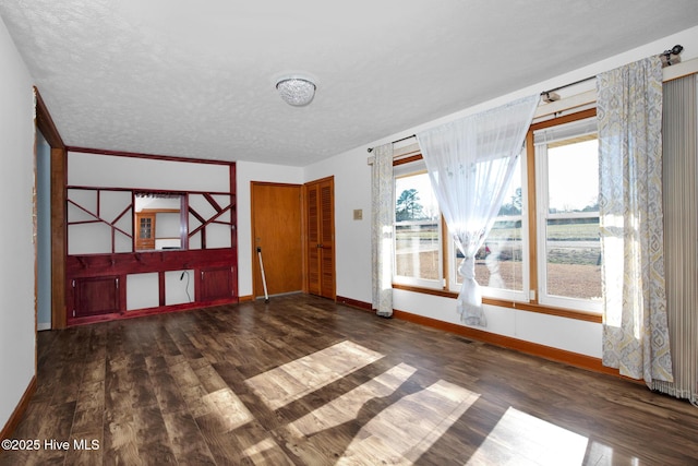 interior space with visible vents, a textured ceiling, baseboards, and wood finished floors