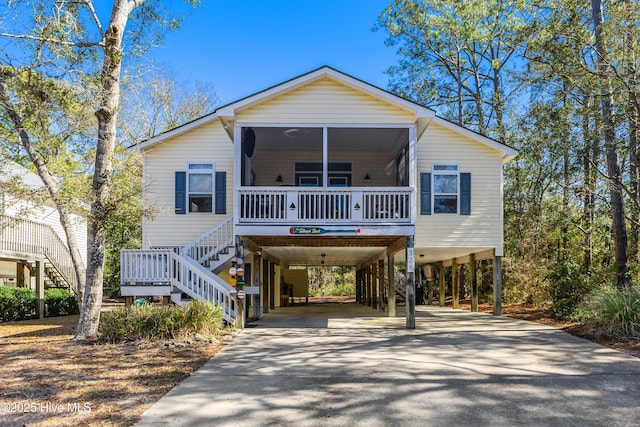 coastal inspired home featuring stairs, a carport, a porch, and driveway