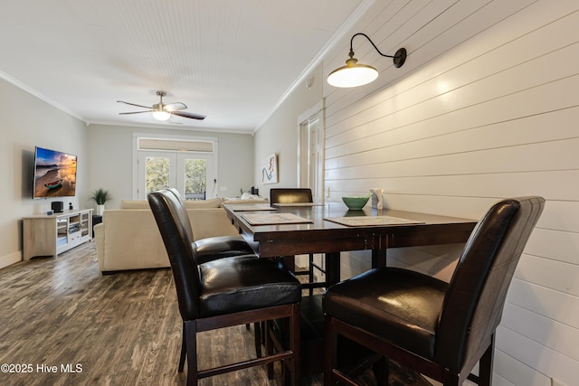 dining space with dark wood-type flooring, crown molding, baseboards, and a ceiling fan