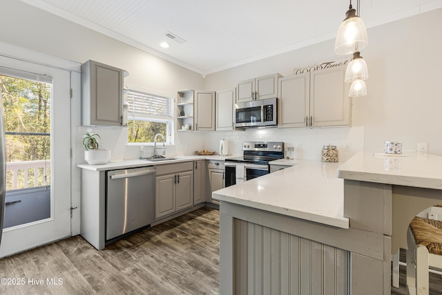 kitchen with ornamental molding, stainless steel appliances, backsplash, and gray cabinetry