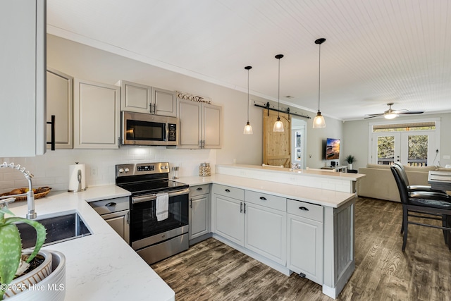 kitchen with a peninsula, open floor plan, appliances with stainless steel finishes, gray cabinets, and crown molding