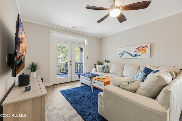 living area featuring ceiling fan, visible vents, french doors, light wood-type flooring, and crown molding