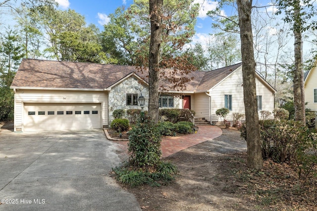 ranch-style home featuring a shingled roof, stone siding, driveway, and an attached garage