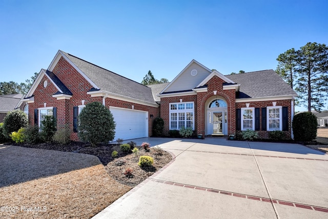 traditional-style house featuring concrete driveway, brick siding, roof with shingles, and an attached garage