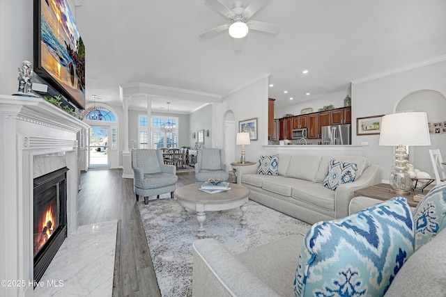 living room with recessed lighting, a fireplace, wood finished floors, a ceiling fan, and ornamental molding