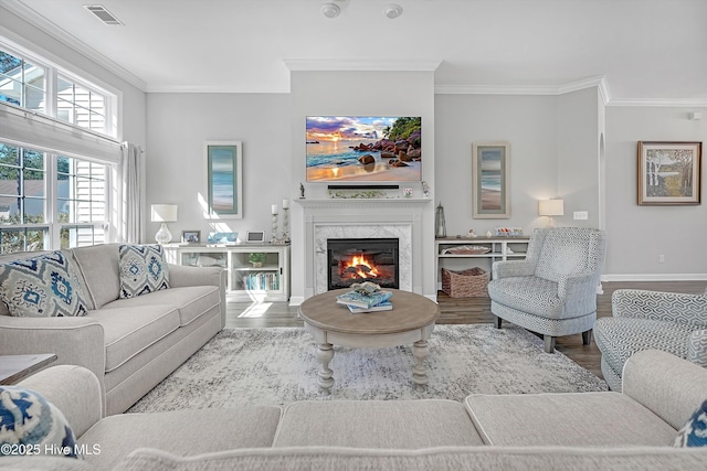 living area featuring visible vents, crown molding, a fireplace, and wood finished floors