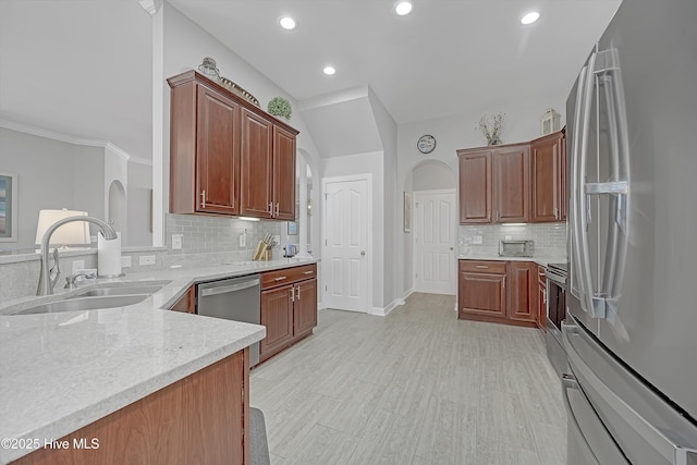 kitchen with tasteful backsplash, baseboards, appliances with stainless steel finishes, light stone counters, and a sink