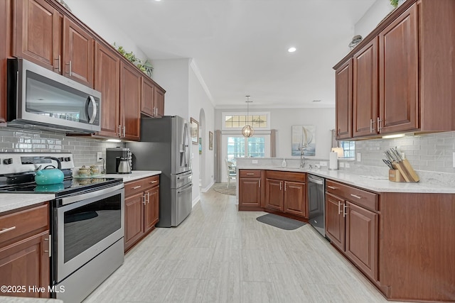 kitchen with stainless steel appliances, a peninsula, light countertops, ornamental molding, and backsplash