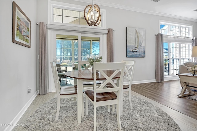 dining room with ornamental molding, wood finished floors, and a notable chandelier