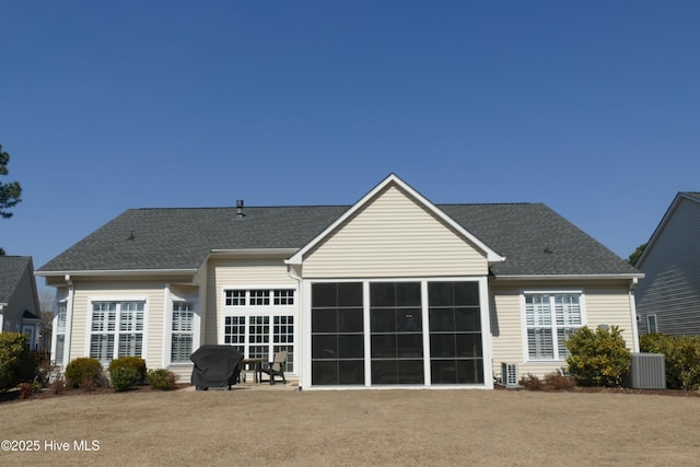 rear view of property with central AC unit, roof with shingles, and a patio area