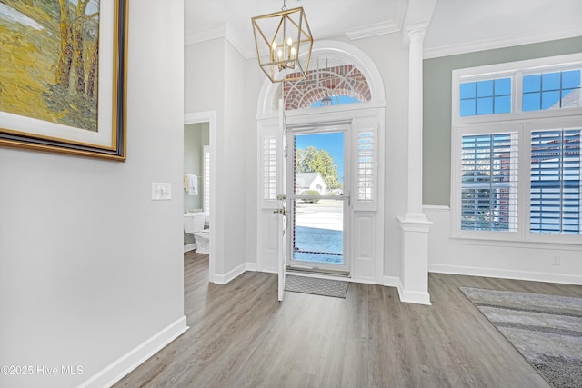 foyer entrance with plenty of natural light, wood finished floors, decorative columns, and crown molding