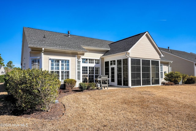 back of property featuring a sunroom, a shingled roof, and a yard