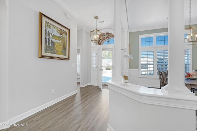 foyer with crown molding, a notable chandelier, and decorative columns