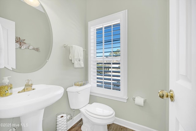 bathroom with toilet, baseboards, a sink, and wood finished floors