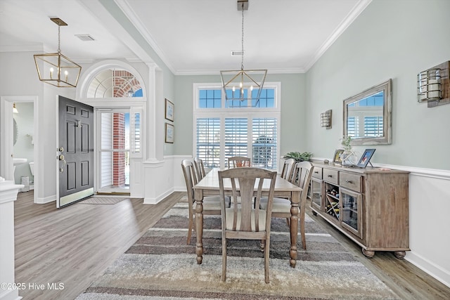 dining space with crown molding, wood finished floors, and a notable chandelier