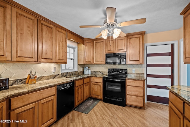 kitchen featuring black appliances, light wood-style floors, a sink, and brown cabinets