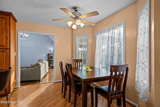 dining room featuring light wood-type flooring, ceiling fan, baseboards, and a textured ceiling