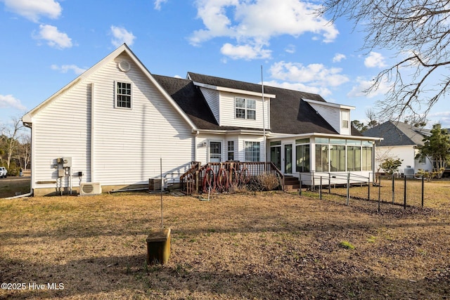 back of house featuring a shingled roof, a sunroom, a lawn, and a wooden deck