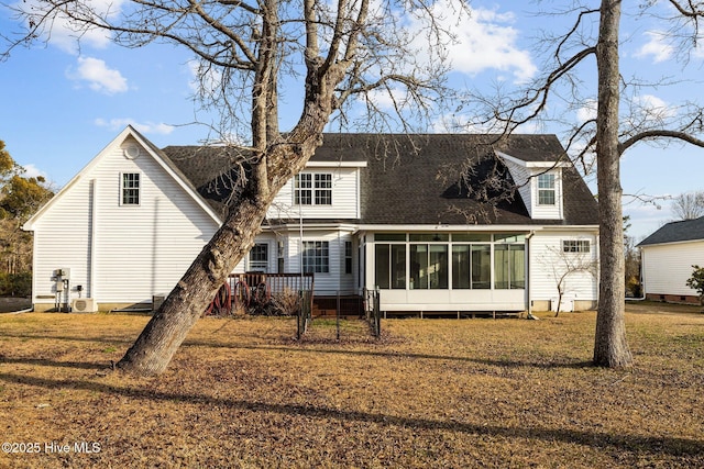 back of house featuring a shingled roof, a sunroom, and a lawn