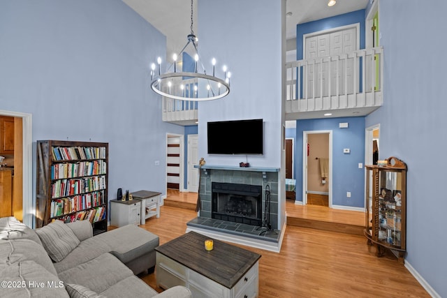 living room with a towering ceiling, a fireplace, baseboards, and wood finished floors