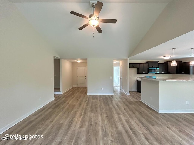 kitchen featuring light wood-style floors, light countertops, stainless steel microwave, and baseboards