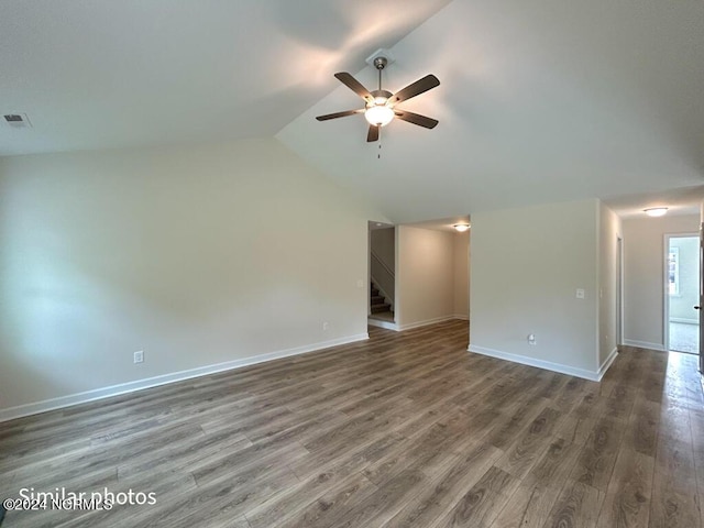 spare room with lofted ceiling, visible vents, baseboards, and wood finished floors