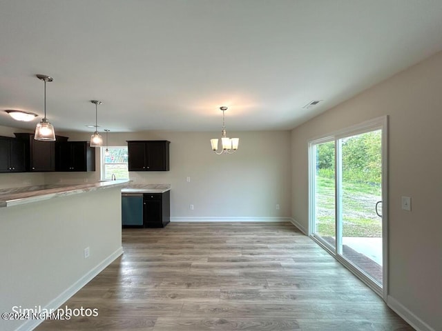 kitchen with a wealth of natural light, a notable chandelier, light wood finished floors, and dishwasher