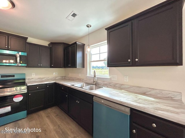 kitchen with light wood finished floors, stainless steel appliances, light countertops, visible vents, and a sink