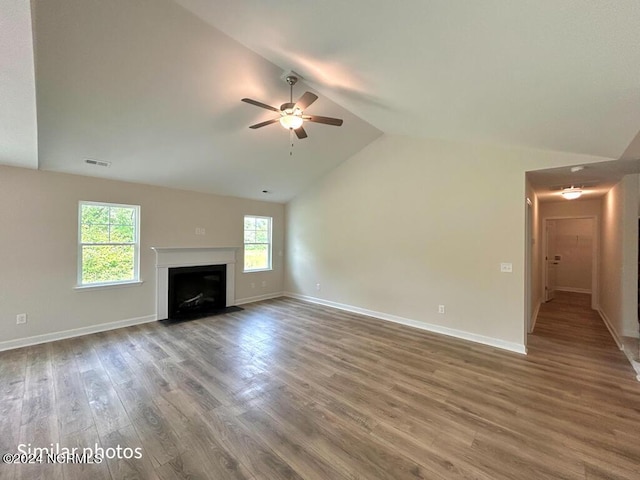 unfurnished living room with baseboards, visible vents, lofted ceiling, a fireplace with flush hearth, and wood finished floors